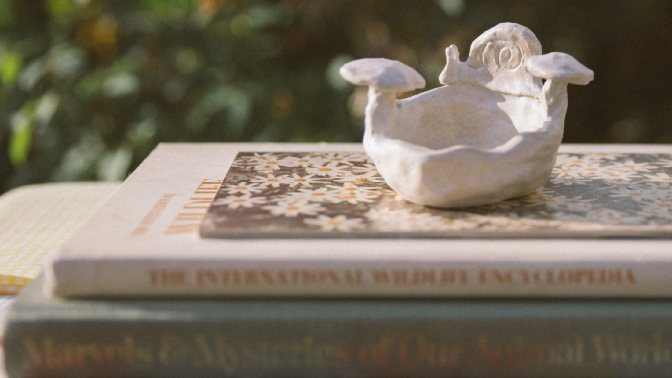 Small white ceramic sculpture of a snail and mushrooms